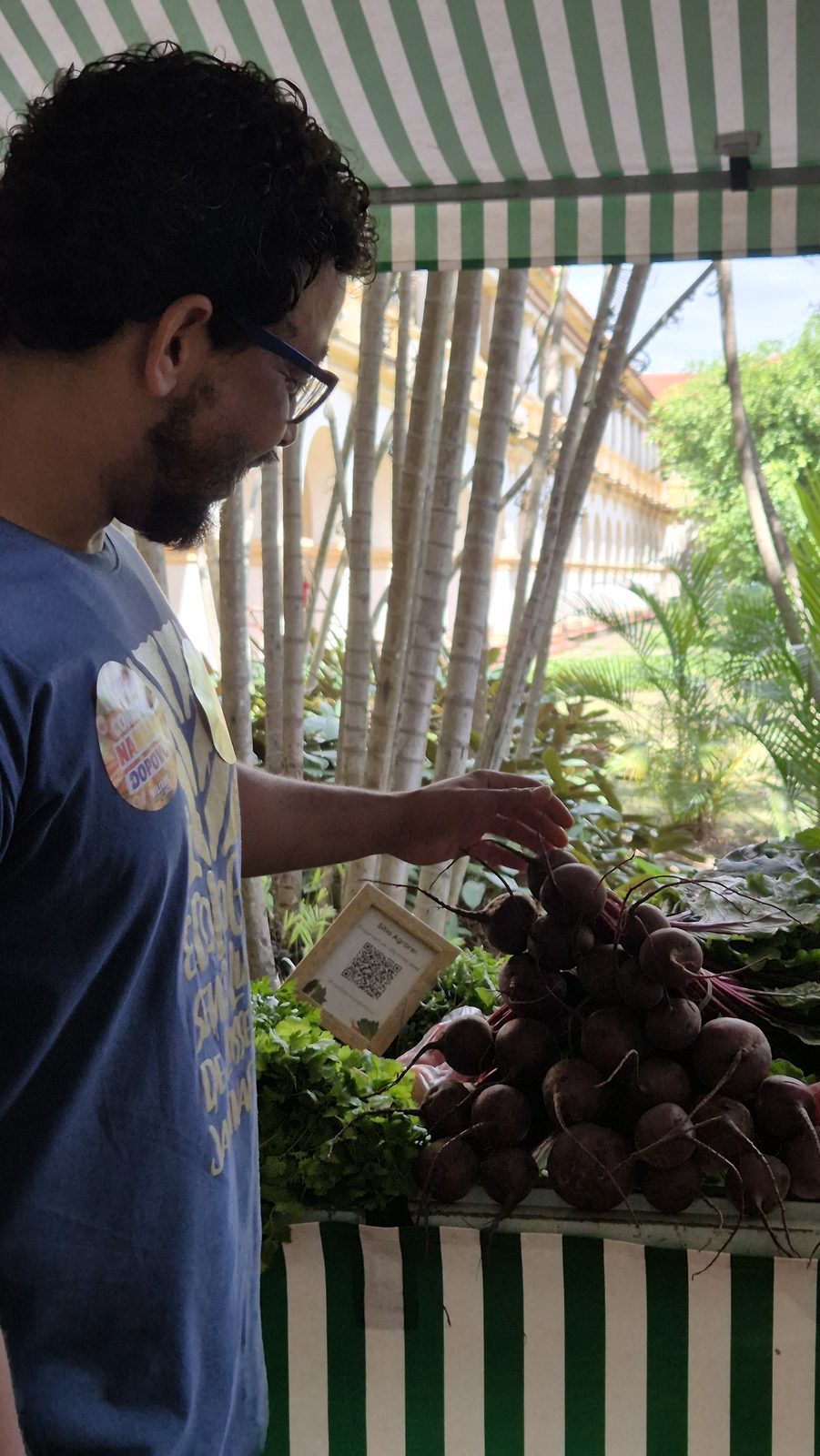 Wilians Douglas escolhe beterrabas na banca de uma feira de agricultura familiar em Seropédica